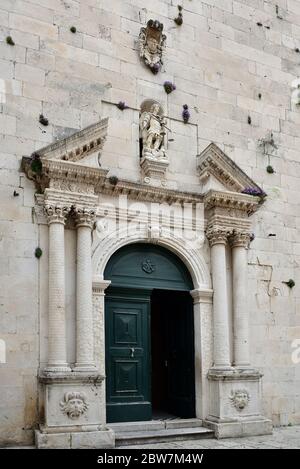 I fiori crescono rigogliosamente sopra l'ingresso principale della chiesa nella città vecchia di Omis, Dalmazia, Croazia Foto Stock