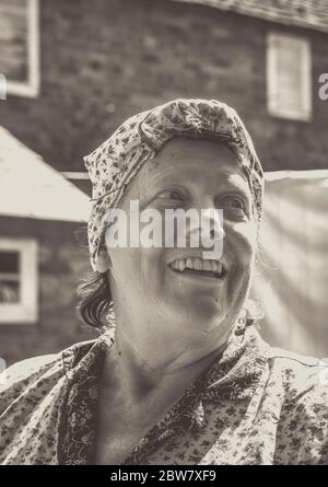 Primo piano monocromatico di sorridente donna degli anni '40, casalinga d'epoca, isolato all'aperto in tute facendo lavanderia casalinghi al sole, 1940 evento della seconda guerra mondiale, Regno Unito. Foto Stock