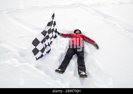 L'uomo giace nella neve con la bandiera del traguardo Foto Stock