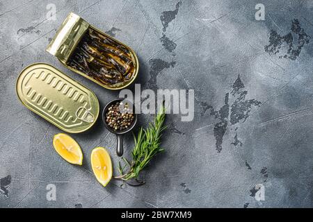 Vista dall'alto di lattine aperte con spratti su tavola in pietra grigia, spazio di visualizzazione superiore per il testo Foto Stock