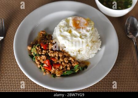 Thai Food, pollo fritto in riso e basilico con uova fritte su piatto bianco. È un popolare menu di Street food thailandese con un forte Filla piccante Foto Stock