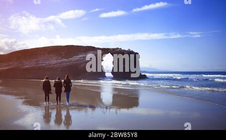 Tre giovani donne sole sulle formazioni rocciose di Playa de las Catedrales Foto Stock