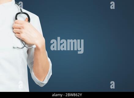 Medico femminile irriconoscibile in camice medico con stetoscopio su sfondo blu. Concetto di assicurazione medica per la sanità Foto Stock