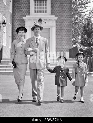 1950 FAMIGLIA DI QUATTRO VESTITI VESTITI MIGLIORI DELLA DOMENICA A PIEDI DALLA CHIESA COSTRUZIONE SORRIDENTE MADRE PADRE RAGAZZO RAGAZZA - C4683 HAR001 HARS SUBURBANA PRIMAVERA MADRI VECCHIO TEMPO NOSTALGIA FRATELLO VECCHIO MODO SORELLA GIOVANILE STILE DI COMUNICAZIONE LAVORO DI SQUADRA MEGLIO SODDISFATTO FAMIGLIE GIOIA STILE DI VITA SODDISFAZIONE RELIGIONE FEMMINE PASQUA SPOSATO DOMENICA FRATELLI CONIUGE MARITI CAPPOTTI SALUTE COPIA SPAZIO AMICIZIA A LUNGHEZZA INTERA SIGNORE PERSONE ISPIRAZIONE AWAY FESTIVAL MASCHI FRATELLI CRISTIANI SPIRITUALITÀ FIDUCIA SORELLE PADRI B&W PARTNER VESTITO E CRAVATTA FELICITÀ ALLEGRO TEMPO LIBERO RELIGIOSO CRISTIANESIMO Foto Stock