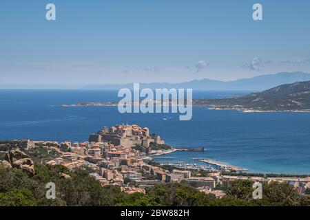 Antica Cittadella e porto di Calvi nella regione Balagne della Corsica circondata dal blu Mar Mediterraneo con Cap Corse in lontananza Foto Stock