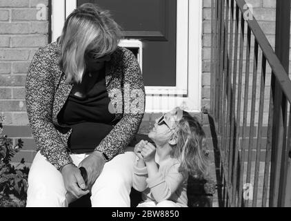 Lockdown ritratto di madre e figlia che si guardano l'un l'altro. Bianco e nero Foto Stock