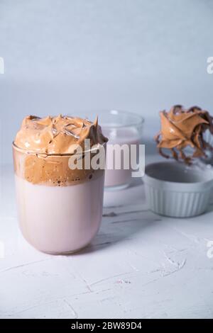 Caffè Dalgona con caffè montato e latte sullo sfondo. Bevanda alla moda coreana. Immagine verticale. Foto Stock