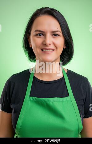 Cuoca femminile con grembiule verde e t-shirt nera, isolata su sfondo verde Foto Stock