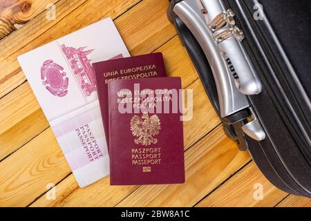 Valigia di viaggio grande e passaporto polacco. Bagagli confezionati preparati per viaggiare all'estero. Sfondo scuro. Foto Stock