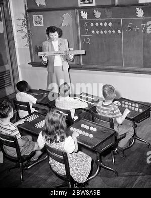 1950 INSEGNANTE ANONIMO DI DONNA E SEI STUDENTI ELEMENTARI IN UNA CLASSE ARITMETICA MATEMATICA AD UNA SCUOLA VEDENTE E DIFFICILE DA ASCOLTARE - S3984 HAR001 HARS INFORMAZIONI LIFESTYLE FEMMINE 6 COPIA SPAZIO MEZZA LUNGHEZZA MASCHI SEI OBIETTIVI B&W SCUOLE VISIONE GRADO ALTO ANGOLO SCOPERTA AFROAMERICANI CONOSCENZA AFROAMERICANA ISTRUTTORE ETNIA NERA VISTA POSTERIORE SENSES OPPORTUNITY SEEING OCCUPATIONS PRIMARY VISUAL AID CONNECTION FROM BEHIND ADDITION ARITMETIC EDUCATOR HEARTING SIGHT BACK VIEW COOPERATION EDUCATORS GRADE ISTRUTTORI SCOLASTICI GIOVANI ADULTI MID-ADULT SCUOLA FEMMINILE INSEGNA TATTILE Foto Stock