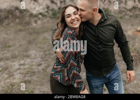 Uomo baciando la donna sorridente mentre cammina in natura. Felice coppia Foto Stock