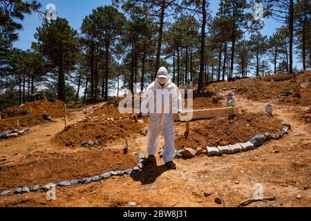 Istanbul, Turchia. 30 maggio 2020. Un operaio di malva che indossa un vestito protettivo è in piedi in un cimitero presso la tomba di una persona che è morto di COVID-19. Credit: Yasin Akgul/dpa/Alamy Live News Foto Stock