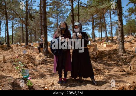 Istanbul, Turchia. 30 maggio 2020. Donne che indossano una maschera protettiva piangere in un cimitero accanto alla tomba recentemente sepolta di un parente morto di COVID-19. Credit: Yasin Akgul/dpa/Alamy Live News Foto Stock