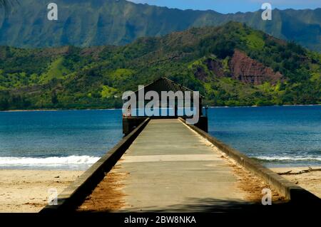 I turisti potranno ammirare la vista dal molo di Hanalei sull'isola di Kauai, Hawaii. La baia offre una splendida vista sulle aspre montagne Kauai. Foto Stock
