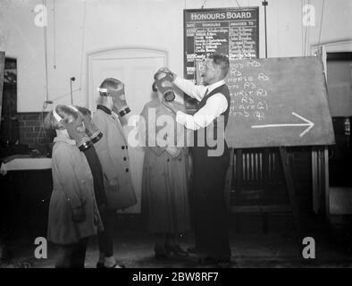 Un insegnante si assicura che i bambini abbiano montato correttamente le loro maschere a gas alla Sidcup Hill School , Londra . 1938 Foto Stock