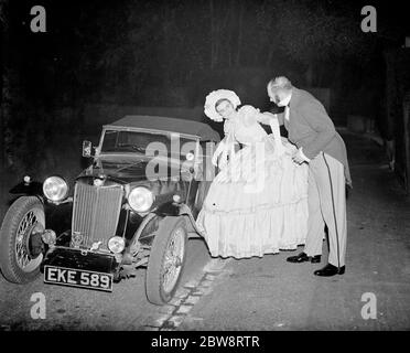 Fotografo , John Topham con Miss Haken , vestito in costume vittoriano entrando in una macchina sportiva a due posti . 1938 Foto Stock