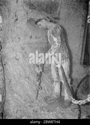 Il completamento del tunnel pilota di Dartford . Un minatore lavora attorno a uno scudo per la perforazione di tunnel con un trapano pneumatico . 11 ottobre 1938 Foto Stock