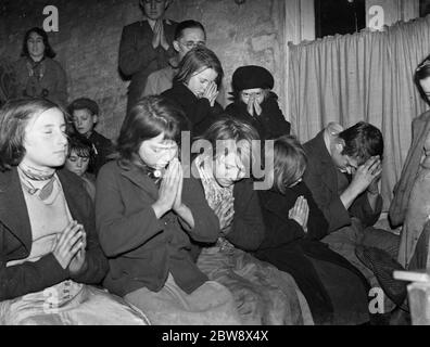 Scuola domenicale per bambini zingari nel capanno di vacca a a Santa Maria Cray . Bambini che pregano . 1939 Foto Stock