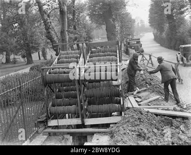 Fasci di cavi telefonici su una culla che vengono posti sottoterra da lavoratori a Chislehurst , Kent . 1939 Foto Stock