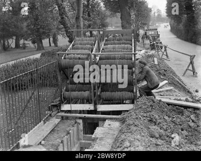 Fasci di cavi telefonici su una culla che vengono posti sottoterra da lavoratori a Chislehurst , Kent . 1939 Foto Stock