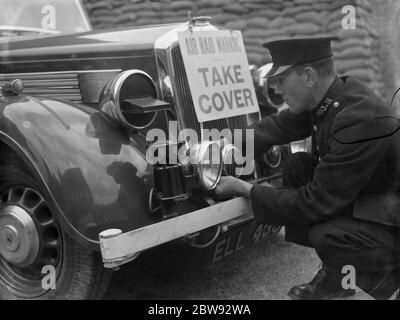 Un poliziotto sta montando una sirena RAID aria insieme ad un segnale di avvertimento ad un'automobile della polizia in Eltham, Kent . 1939 Foto Stock