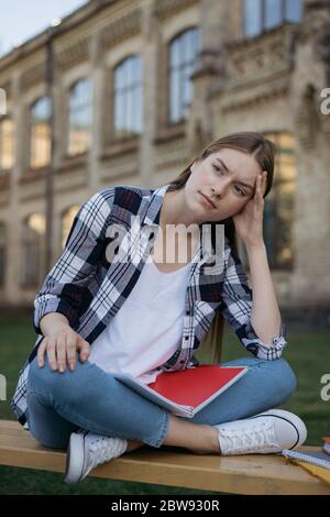 Studente deluso dai risultati degli esami. Ritratto di donna infelice con viso stanco e triste seduta su panchina, lei perde speranza. Concetto di errore degli esami Foto Stock