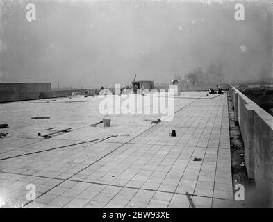 Lavoratori della Val De Travers Asphalt Limited , una società di pavimentazione , che lavora su un tetto a Greenwich , Londra . 1938 Foto Stock