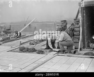 Lavoratori della Val De Travers Asphalt Limited , una società di pavimentazione , che lavora su un tetto a Greenwich , Londra . 1938 Foto Stock