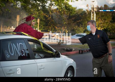 Marietta, GA, Stati Uniti. 29 maggio 2020. Un anziano alla Lassiter High School a nord di Atlanta, riceve il suo diploma dal Dott. mascherato principale Chris Richie, in una parata di centinaia di studenti intorno al campo scolastico. La parata ha utilizzato misure di distanza sociale invece della più tipica passeggiata in auditorium in riconoscimento della minaccia di infettare gli altri con il virus Covid-19. Credit: Robin Rayne/ZUMA Wire/Alamy Live News Foto Stock