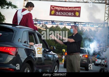 Marietta, GA, Stati Uniti. 29 maggio 2020. Un anziano della Lassiter High School a nord di Atlanta, riceve il suo diploma dal direttore mascherato Dr. Chris Richie, in una sfilata di centinaia di studenti intorno al campo scolastico. La parata ha utilizzato misure di distanza sociale in auto personali invece della più tipica passeggiata in auditorium fase in riconoscimento della minaccia di infettare gli altri con il virus Covid-19. Credit: Robin Rayne/ZUMA Wire/Alamy Live News Foto Stock