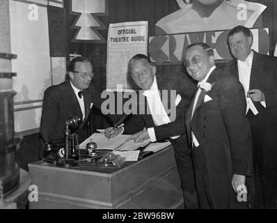 Il regista britannico che ha fatto Grand Hotel partecipa alla prima notte di film a Londra . Tra le personalità che hanno partecipato alla presentazione in anteprima del film di Grand Hotel al Palace Theatre di Londra c'era Edmund Goulding , il regista britannico che ha realizzato il film . Il signor Goulding era un ex macellaio a Londra, ma ora è uno dei principali registi di Hollywood e ha trionfato nel suo compito senza precedenti di dirigere cinque stelle famose in questo quadro . Edmund Goulding (a destra) con Leslie Henson (a sinistra) e Sam Eckman Jr della Metro Goldwyn Meyer (centro) che firmano il registro dell'hotel Foto Stock