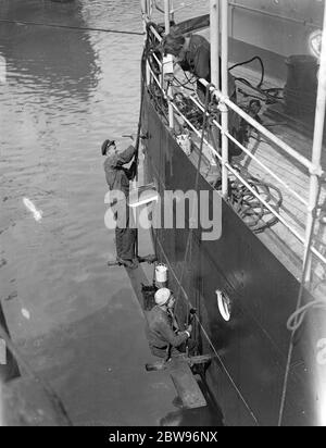 Le donne sovietiche dipingono la loro nave nel Tamigi . Due ragazze russe , due delle sole cinque marinai russe , che lavorano come marinai ordinari con le mani degli uomini , sono occupate sulla loro nave , la Copoperatzia , motonave sovietica a Hayes Wharf , Londra dipingendo i lati della nave . Dopo due anni in mare si prevede che si qualifichino come terzo ufficiale . Anikin , una delle ragazze marinai , dipingendo il lato della sua nave in compagnia con una mano di uomo , mentre la sua ragazza compagno guarda dal ponte superiore . 23 luglio 1932 Foto Stock