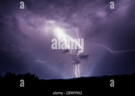 Potente e drammatico doppio fulmine che cade a terra durante la tempesta pesante sulle montagne della Romania Foto Stock