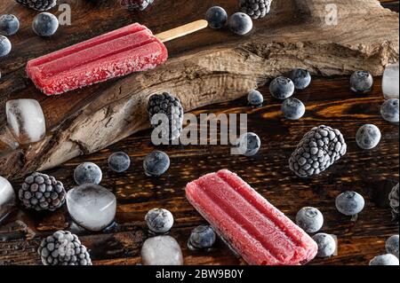 Bacche surgelate, lecci di ghiaccio e cubetti di ghiaccio su un asse di legno Foto Stock
