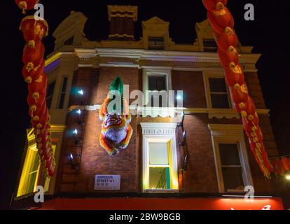 Wardour Street a Londra, China Town, con un drago cinese e lanterne appese al muro di mattoni di un negozio. Londra Foto Stock