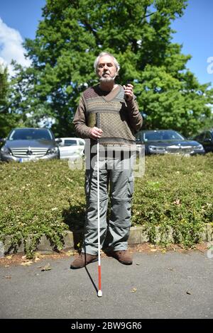 Berlino, Germania. 26 Maggio 2020. Manfred Scharbach, presidente dell'Associazione Generale per non vedenti e non vedenti, ascolta l'uscita vocale del suo cellulare. Smartphone e tablet rendono la vita molto più facile per molti ciechi. Anche i classici come le lenti d'ingrandimento e i pali lunghi stanno diventando più moderni. (A 'Smartphone e Mini Camera - come la tecnologia aiuta i ciechi') credito: Sven Braun/dpa/Alamy Live News Foto Stock