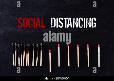 Concetto di allontanamento sociale. Matchsticks bruciare, un pezzo impedisce il fuoco di diffondersi lontano dall'altro utilizzando il concetto di allontanamento sociale per fermare t Foto Stock