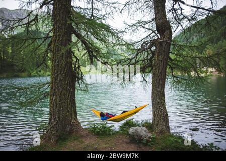 Svizzera, Bravuogn, Palpuognasee, giovane donna che riposa in amaca vicino al lago Palpuognasee nelle Alpi svizzere Foto Stock