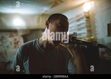 Giovane uomo che canta durante le prove in garage Foto Stock