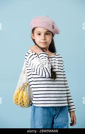 Ritratto di una bambina alla moda in beretto francese che tiene borsa con banane Foto Stock