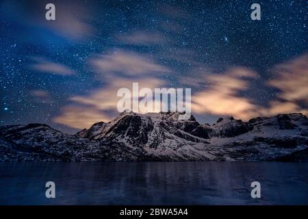 Un rilassante colpo di stelle sulle catene montuose innevate del lago Storvatnet, Norvegia Foto Stock