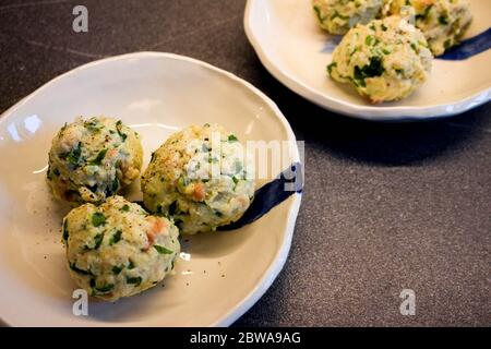 Tre gnocchi di pane tradizionali tedeschi con aglio selvatico su grandi piatti di ceramica bianca fatti a mano con strisce blu Foto Stock