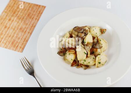 gnocchi con funghi, in una piastra bianca, su un tavolo bianco Foto Stock