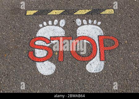 Poole, Dorset UK. 31 maggio 2020. Segnale di stop con impronte sul marciapiede a Poole - segnaletica per pavimentazione. Credit: Carolyn Jenkins/Alamy Live News Foto Stock