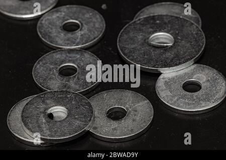 immagine in bianco e nero di alcune rondelle metalliche di varie dimensioni sparse su un pavimento in legno di tipo parquet Foto Stock