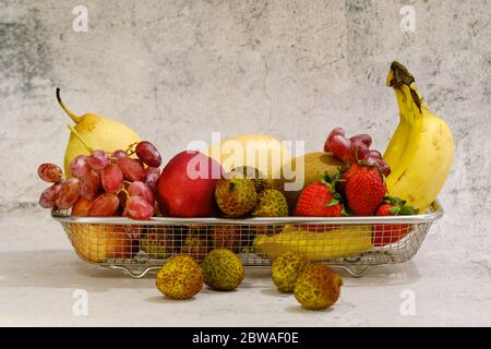 Assortimento di frutta esotica in basket di metallo isolato su bianco Foto Stock