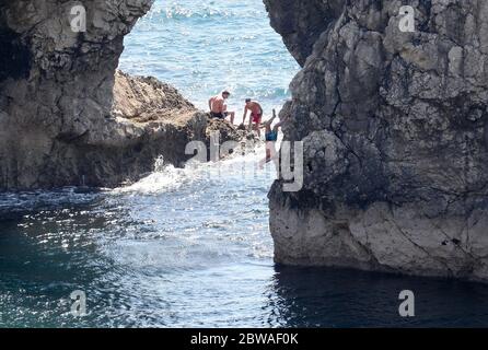 Una persona salta in mare da Durdle Door, vicino a Lulworth, nonostante Dorset Council annunciasse che la spiaggia era chiusa al pubblico dopo che tre persone sono state gravemente ferite saltando dalle scogliere in mare. Foto Stock