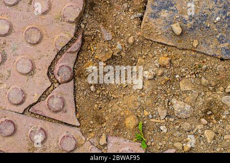 Marciapiede in costruzione. Struttura di pavimentazione tattile rotta con terreno. Foto Stock