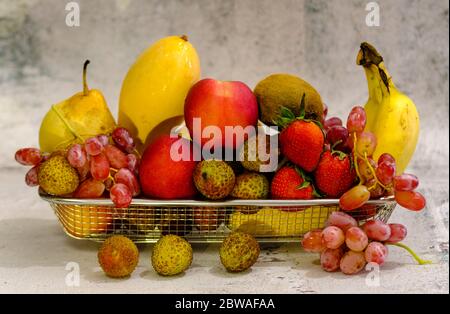 Assortimento di frutta esotica in basket di metallo isolato su bianco Foto Stock