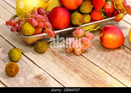 Assortimento di frutta esotica in cestello di metallo isolato su legno Foto Stock